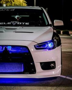 the front end of a white car with blue lights