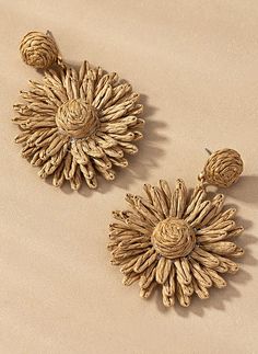 two pairs of earrings on a beige surface