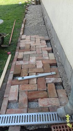 a brick walkway is being installed in front of a house with tools on the ground