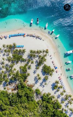 an aerial view of a beach with boats in the water and palm trees around it