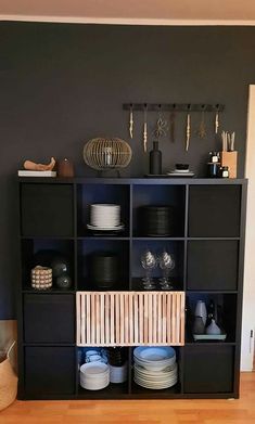 a black bookcase with plates and bowls on top of it in a living room