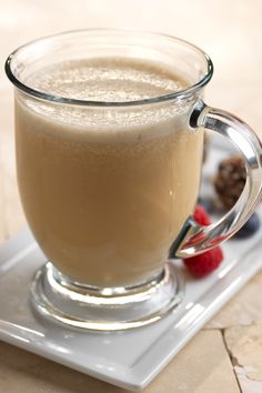 a glass mug filled with liquid sitting on top of a white plate