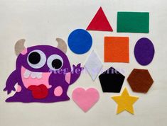 an assortment of felt shapes and colors on a white surface, including a purple monster with big eyes