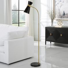 a living room with a white couch, black and gold floor lamp and large windows