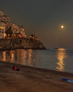 a full moon shines in the sky over some buildings and boats on the water