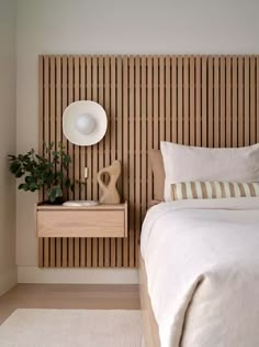 a white bed sitting next to a wooden headboard with a plant on it's side