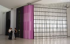 two people are standing in front of a curtained wall with black and white stripes