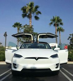 two white tesla cars parked in a parking lot with open hoods on the top