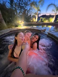 three women in a hot tub at night with their arms around each other as they take a selfie