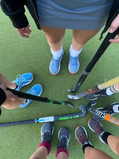 a group of people standing in a circle holding baseball bats and shoes on the ground