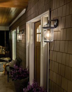 two lights on the side of a house next to potted plants and flowers outside