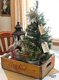 a small christmas tree in a wooden crate on a dining room table with two chairs