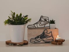 a pair of sneakers sitting on top of a wooden block next to a potted plant