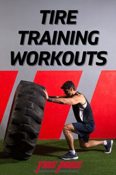 a man holding a large tire while standing in front of a red and white sign