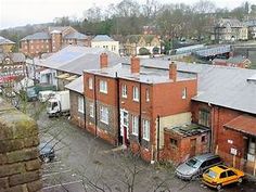 an old brick building with cars parked in the parking lot and buildings on either side