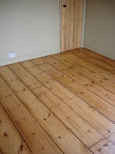 an empty room with wood floors and white walls