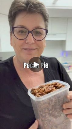 a woman holding a plastic container filled with nuts