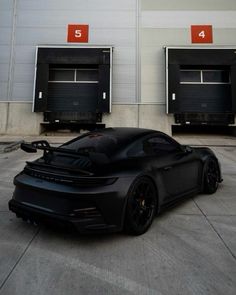 a black sports car parked in front of three doors