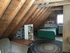 an attic bedroom with a bed, chair and bookcase in it's corner