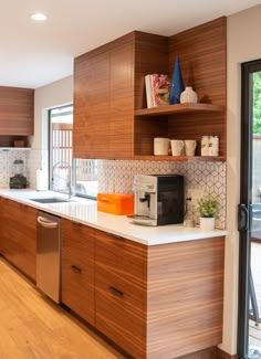 a kitchen with wooden cabinets and white counter tops, along with an open door leading to the outside patio