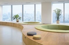 an empty room with circular seating and plants in the window sill, looking out on cityscape