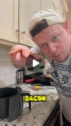 a man standing in front of a stove top oven holding something up to the camera