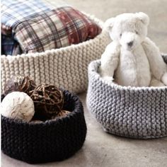 three crocheted baskets with stuffed animals in them, one is white and the other is black