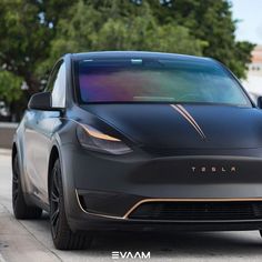 an electric car is parked on the side of the road with trees in the background