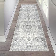 a white and gray rug on the floor in a hallway next to a refrigerator freezer