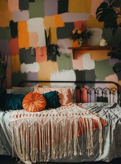 a bed with pillows and blankets on it in front of a wall painted with colorful squares