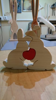 two wooden rabbits sitting next to each other on top of a table in a room