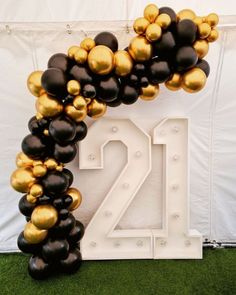 an arch made out of balloons with the number twenty two in gold and black colors