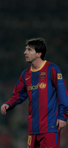 a man in a red and blue soccer uniform looking up at the sky with his hand on his hip