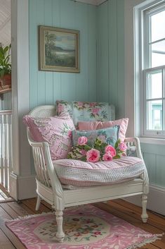 a white chair with pink flowers on it sitting in front of a window and rug