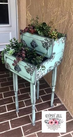 two blue planters with plants in them sitting on a brick floor next to a door