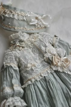 an old fashioned dress and bonnet are laying on the bed together, with lace trimming around the edges