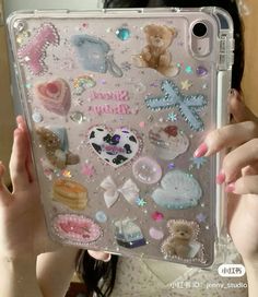 a woman holding up a clear case with lots of stickers on the back of it