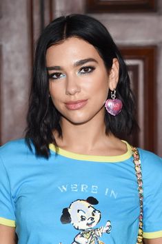 a woman with black hair and blue eyeshadow wearing a t - shirt that has a cartoon character on it