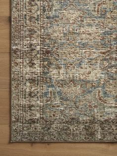 an area rug with various colors and patterns on top of a wooden floor next to a wall