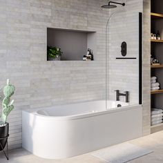 a white bath tub sitting next to a shelf filled with towels