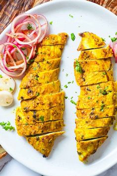 two fish fillets on a white plate with onions and radishes next to it