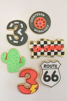 several decorated cookies are arranged in the shape of numbers and cars on a white surface