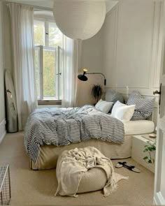 a bedroom with a bed, window, and rug on the floor in front of it