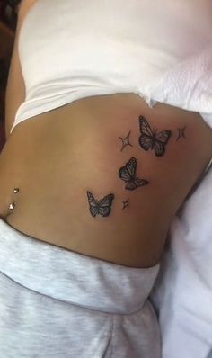 a woman's stomach with three butterflies tattoo on her belly and the bottom part of her stomach