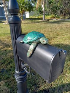 a green turtle sitting on top of a mailbox