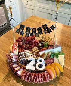 a happy birthday cake with lots of meat and cheeses on the table in front of it