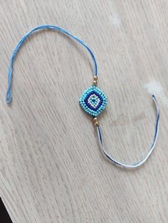 a beaded bracelet on a wooden table with blue string and beads hanging from it