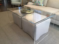 a glass coffee table sitting on top of a carpeted floor next to a couch