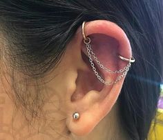 a woman's ear is shown with two chains attached to the end of it