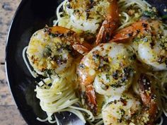 pasta with shrimp and parmesan cheese in a black bowl on a marble table